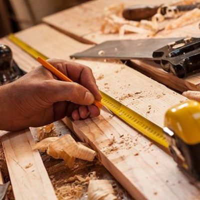 carpenter taking measurement of a wooden plank
